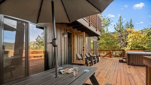 Un terrazzo in legno con posti a sedere all'aperto, una vasca idromassaggio e una zona coperta con tavolo e sedie.