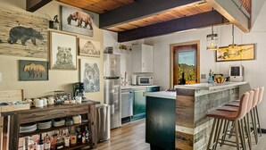 Una cucina moderna con isola centrale, travi in legno e opere d'arte a tema orso.