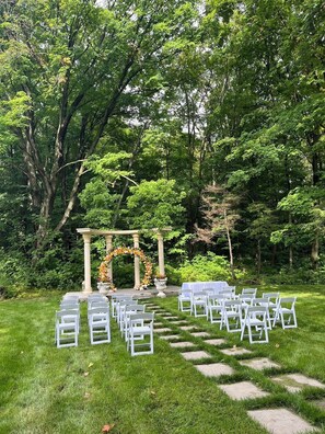A garden wedding setup with white chairs and a floral archway. - Forest Villa for Large Group with Outdoor Pool and indoor Swim Spa-Pet friendly (Newmarket)