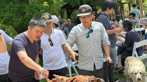 A group of people gathered around a large roasted animal on a grill outdoors. - Forest Villa for Large Group with Outdoor Pool and indoor Swim Spa-Pet friendly (Newmarket)