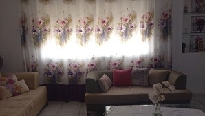 Ein Wohnzimmer mit zwei Sofas, einem Couchtisch und einem blumigen Vorhang.