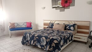 Ein Schlafzimmer mit einem Bett, Nachttischen, einer Bank und einem Wandbild.