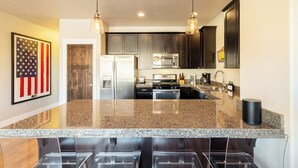 A modern kitchen with granite countertops, stainless steel appliances, and dark cabinetry.