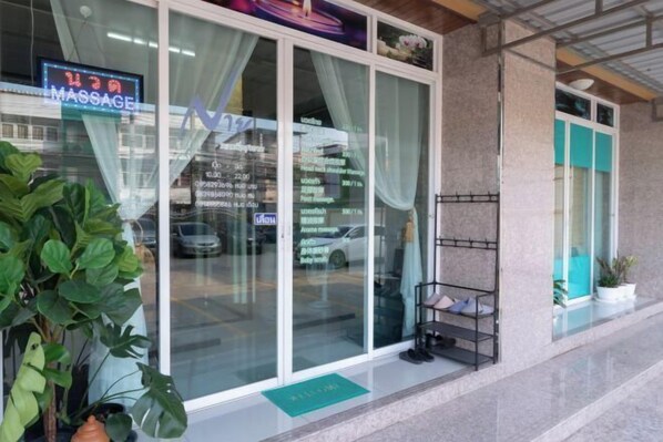 A massage parlor with large glass windows, a reception desk, and a small seating area outside. - Nicha Residense Hotel (Bangkok)