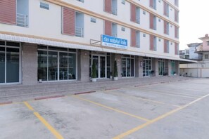 A multi-story building with a sign indicating a business or service establishment. There is a parking area in front with marked spaces. - Nicha Residense Hotel (Bangkok)