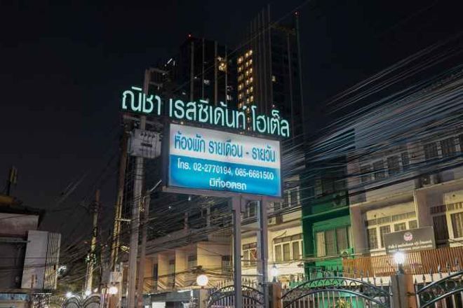 A sign with Thai text and a contact number for a hotel.