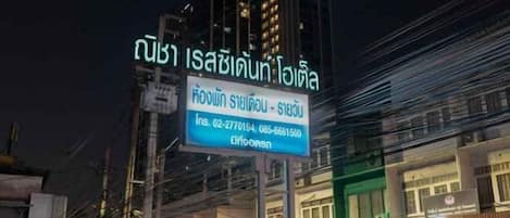 A sign with Thai text and a contact number for a hotel.