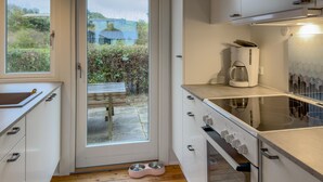 A modern kitchen with white cabinets, a coffee maker, and a glass door leading to a patio. - Lovely home in Knebel with WiFi (Knebel)