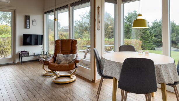 A modern living room with a leather armchair, a round dining table, and a television. - Lovely home in Knebel with WiFi (Knebel)