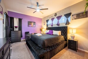 A bedroom with a large bed, a ceiling fan, a dresser, and a nightstand with a lamp. - Colorful Casa!- Pool & lakeviews (Davenport)