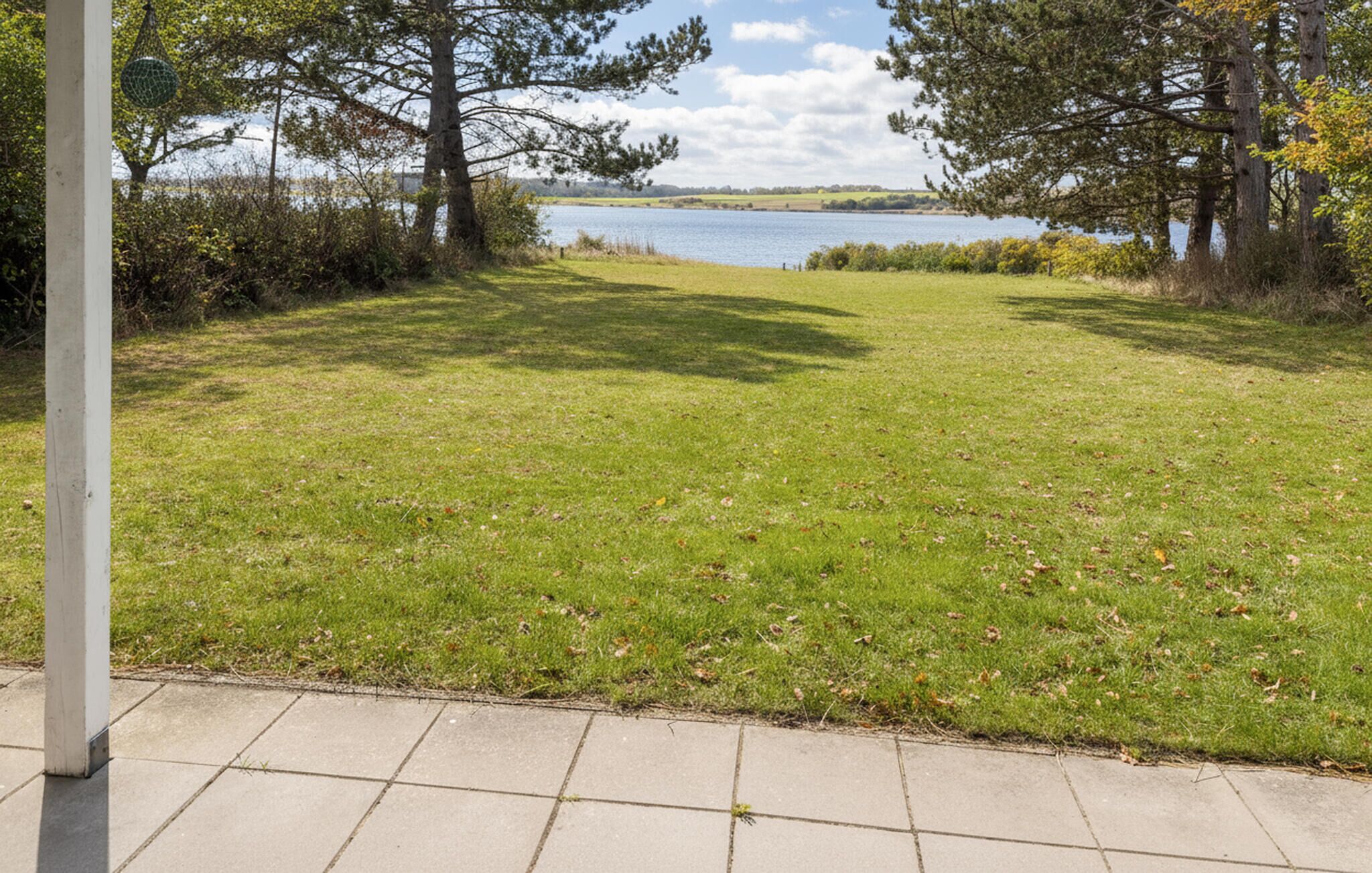 A grassy area with a view of a lake and trees.