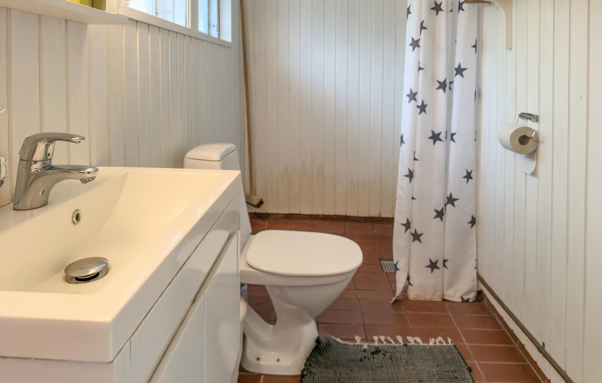 A bathroom with a white sink, a white toilet, and a shower curtain with star patterns.