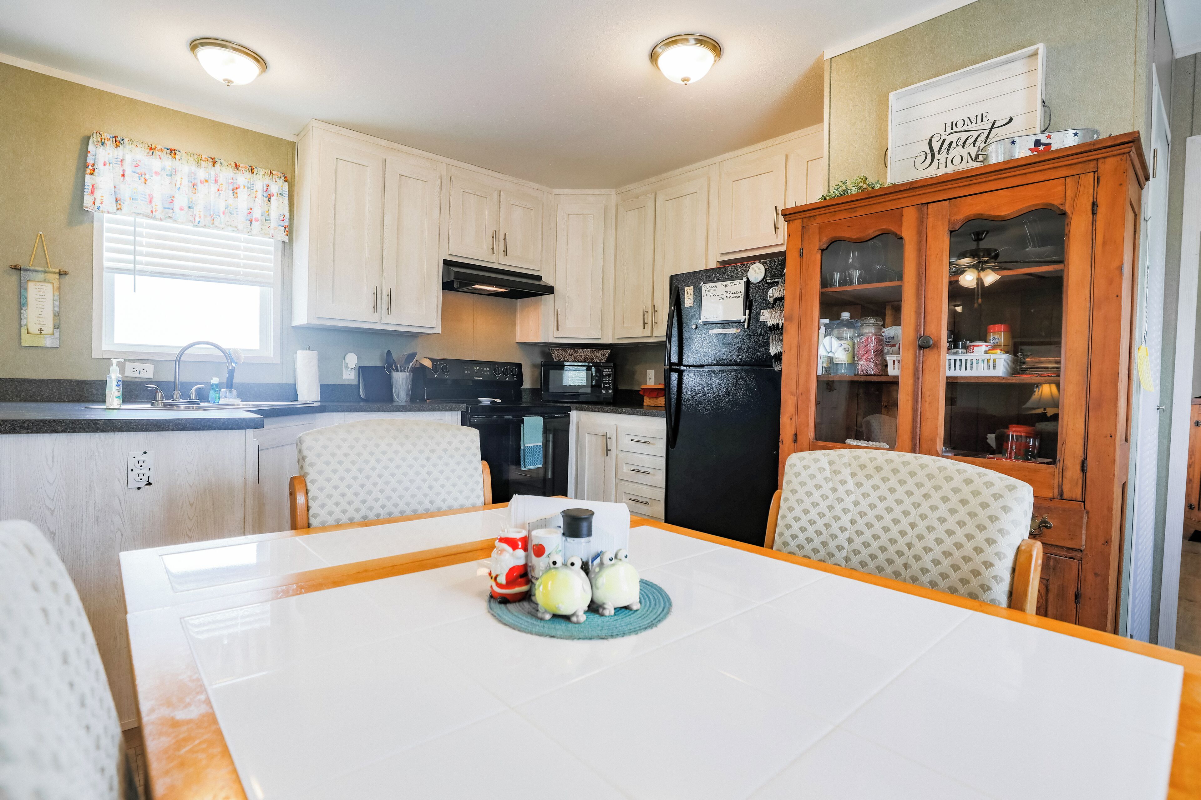 A kitchen with white cabinets, a black refrigerator, and a dining table with chairs.