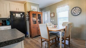 A kitchen with wooden cabinets, a black refrigerator, a dining table with four chairs, and a clock on the wall. - 3 BEDROOM, 2 BATHROOM, POND, SLEEPS 6 (Rockport)