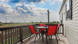 A wooden deck with a table and red chairs, overlooking a grassy area and a house with white siding. - 3 BEDROOM, 2 BATHROOM, POND, SLEEPS 6 (Rockport)