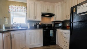 A kitchen with white cabinets, a black stove, and a refrigerator. - 3 BEDROOM, 2 BATHROOM, POND, SLEEPS 6 (Rockport)