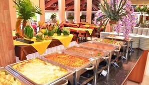 Un buffet proposant une variété de plats, des tables recouvertes de nappes jaunes et agrémentées de plantes décoratives.