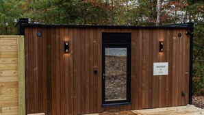 Une cabane en bois avec une porte noire, une petite fenêtre et une enseigne sur laquelle on peut lire « heartleaf ».