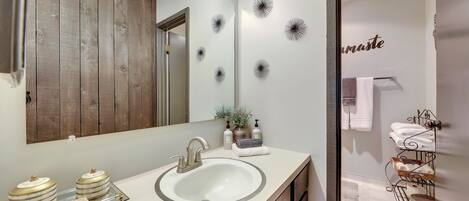 A bathroom with a large mirror, vanity, sink, and towel rack.