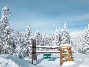 A snow-covered landscape with a wooden signpost indicating 'Welcome' and 'Base Elev. 9600 ft.' - The Nest at Brian Head (Brian Head)