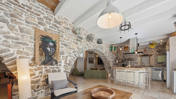 A rustic interior with stone walls, a wooden dining table, a bar area, and a kitchen. - Bardelours 1 – Charming house with swimming pool in the heart of the Pic Sa (Saint-Bauzille-de-Montmel)