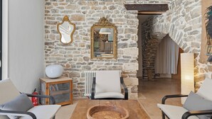 A room with stone walls, a wooden table, a white chair, and a mirror with an ornate frame. - Bardelours 1 – Charming house with swimming pool in the heart of the Pic Sa (Saint-Bauzille-de-Montmel)