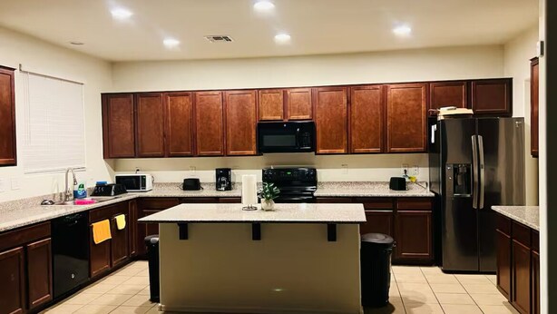 Een moderne keuken met houten kastjes, een centraal eiland, een magnetron, een fornuis en een koelkast.