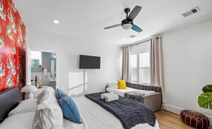 Bright modern bedroom with TV, cozy window daybed, and stylish accent wall