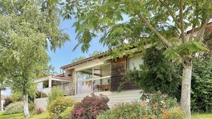 Ein zweistöckiges Haus mit einem Balkon, umgeben von üppiger Vegetation und blühenden Pflanzen.