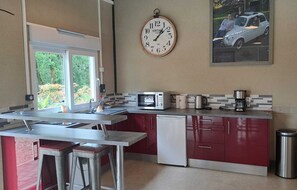 A compact kitchen with a microwave, coffee maker, and a vintage clock on the wall.