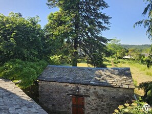 Un bâtiment en pierre avec un toit en pente, une porte en bois et un mur en pierre.