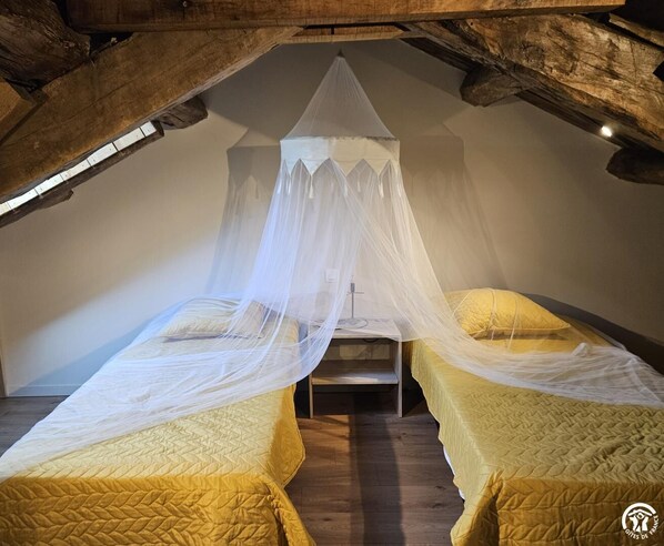 A room with two beds, each with a canopy, and a wooden ceiling structure.