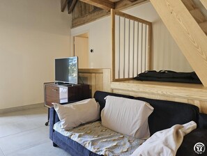 Ein Schlafzimmer mit einem Bett, einem Fernseher auf einer Kommode und einer Holztreppe.