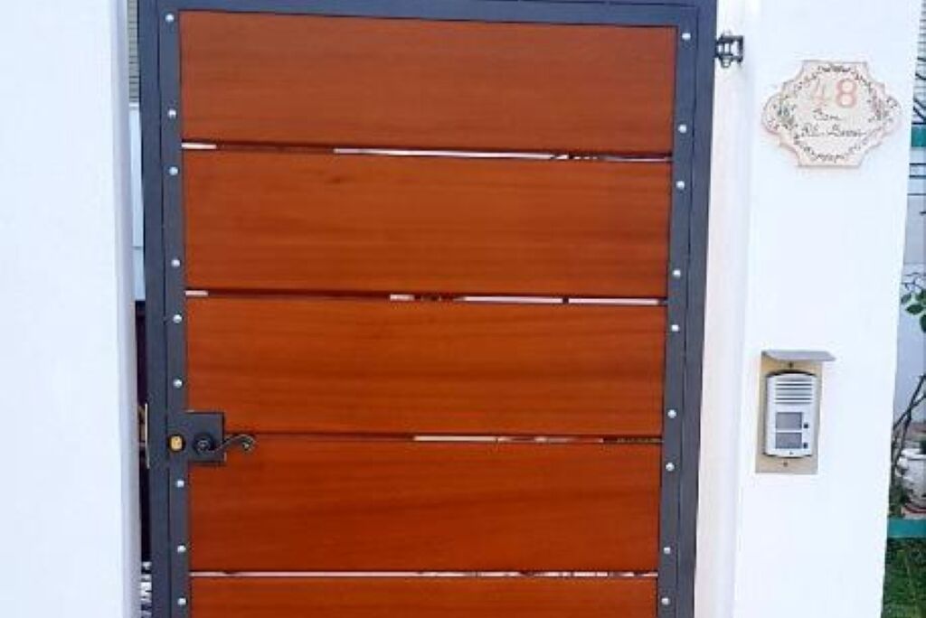 A wooden door with a metal frame and a small electronic device mounted on the wall to its right.