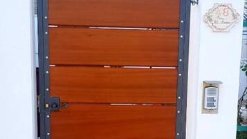 A wooden door with a metal frame and a small electronic device mounted on the wall to its right.