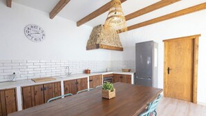 A kitchen with a wooden table, white tiled backsplash, and a stone fireplace.