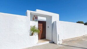 A white building with a door and a small plant in a planter.