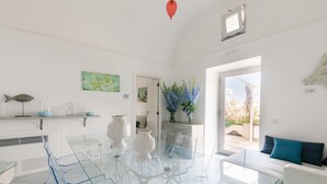 A modern kitchen with a glass dining table, white cabinets, and a view to the outside. - Villa Tirrena by My Villa Collection (Positano)