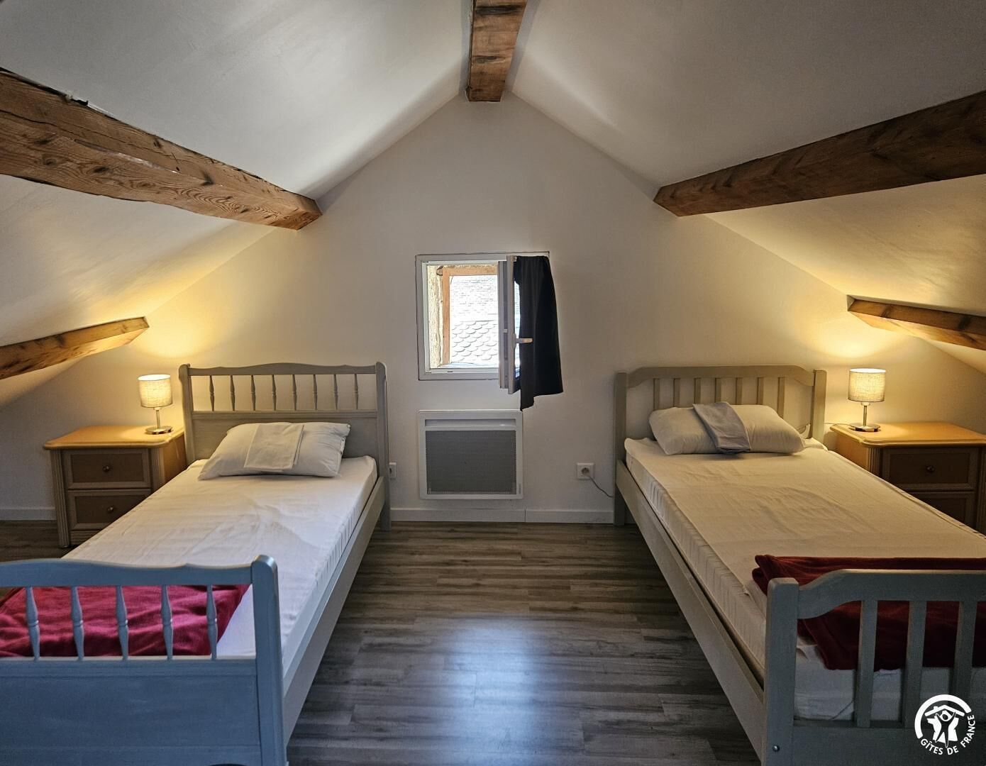 Een slaapkamer met twee bedden, een raam en houten balken.