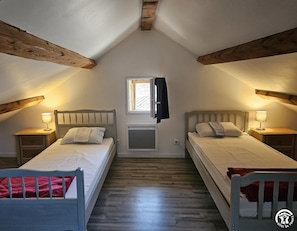 Ein Schlafzimmer mit zwei Betten, einem Fenster und Holzbalken.
