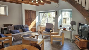 Een gezellige zithoek met een bank, stoelen, een tafel en een televisie.