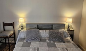A bedroom with a bed, two bedside lamps, a chair, and a nightstand.