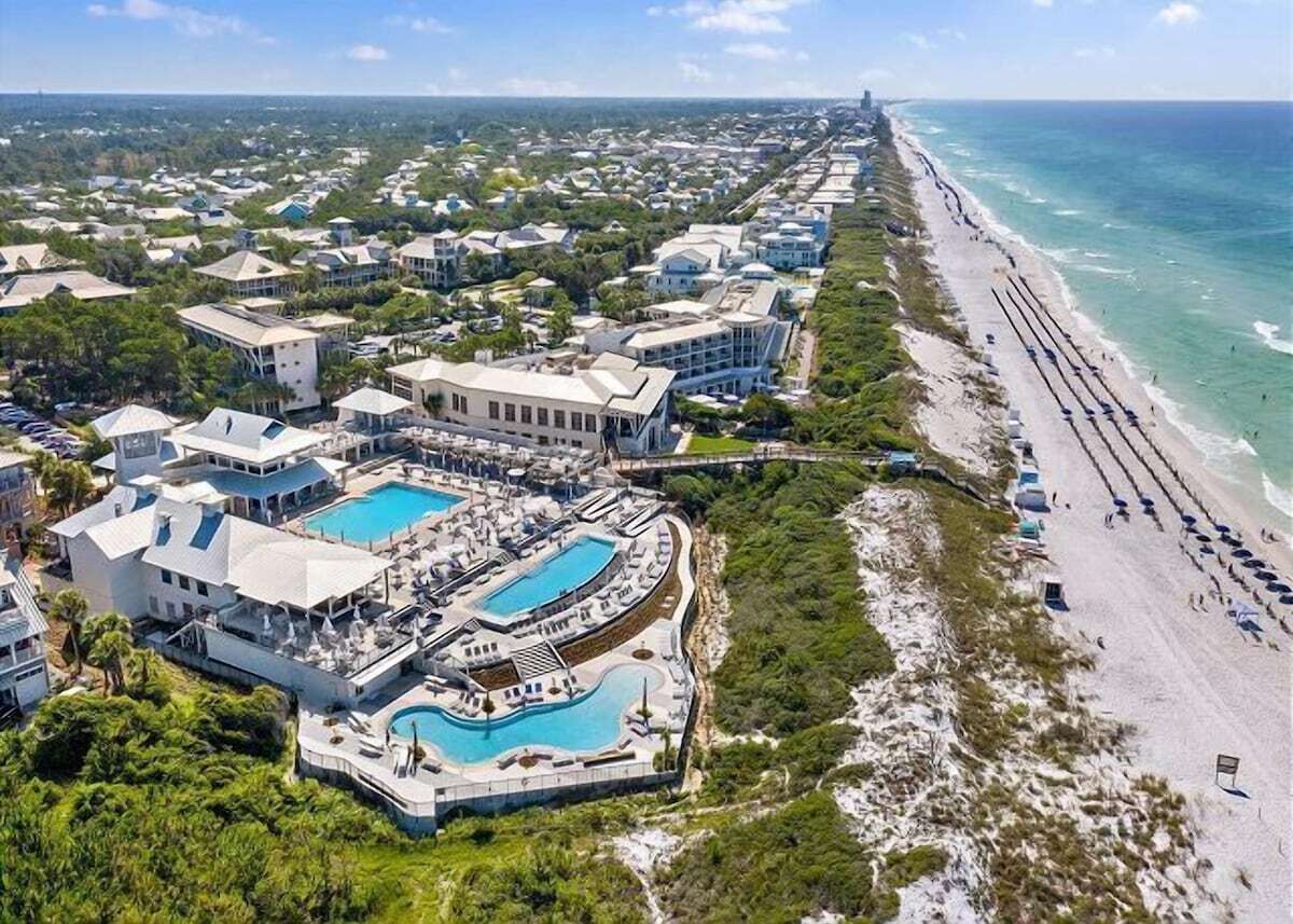 A coastal resort with multiple buildings, a large swimming pool, and a beach.
