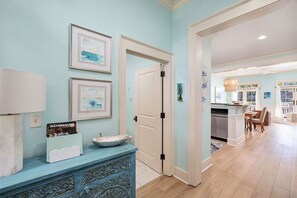 Ein Zimmer mit einer hellblauen Wand, einer weißen Tür, einem blauen Konsolentisch mit einem dekorativen Schrank und einem gerahmten Bild.