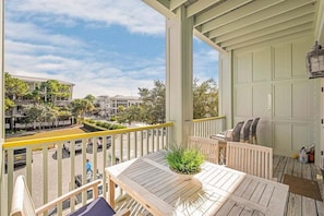 A balcony with a wooden table, chairs, and a potted plant.
