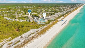 Vista aérea de un complejo turístico frente al mar, con propiedades en primera línea de playa, una zona de piscina y un océano azul cristalino.
