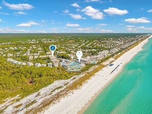 Vista aerea di un resort costiero con proprietà sulla spiaggia, area piscina e oceano blu cristallino.