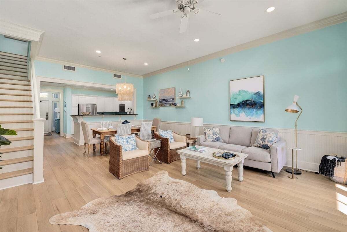 A spacious living room with a dining area, a staircase, and a kitchen in the background.