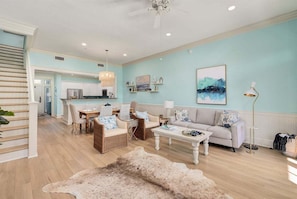 A spacious living room with a dining area, a staircase, and a kitchen in the background.