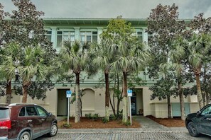 Ein Gebäude mit grüner Fassade, Palmen und zwei Behindertenparkplätzen.